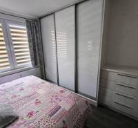 Schlafzimmer mit Einbauschrank und Blumenüberwurf in einer 3-Zimmer-Wohnung.
