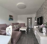 Wohnzimmer in einer 3-Zimmer-Wohnung, mit einem Sofa, dekorativen Möbeln und einem Fernseher an der Wand.