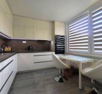 Küche in einer 3-Zimmer-Wohnung mit Sitzgelegenheit und großem Fenster mit Jalousien.