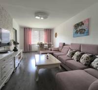 Wohnzimmer mit Sofa und Tisch in einer 3-Zimmer-Wohnung, helle Wände, Fernseher auf dem Schrank.