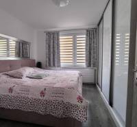 Schlafzimmer in einer 3-Zimmer-Wohnung mit einem großen Bett, einem Einbauschrank und einem Fenster mit Vorhängen.