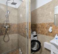 Badezimmer mit Dusche und Waschmaschine in einer 3-Zimmer-Wohnung.