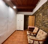 Steinwand, zwei Sessel, weißer und hölzerner Kleiderschrank, Keramikboden.