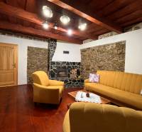 Wohnzimmer in einem Einfamilienhaus mit einem Steinkamin, gelben Sofas und Holzboden.