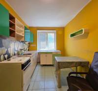 Küche mit gelben Wänden und grünen Schränken in einer 2-Zimmer-Wohnung.