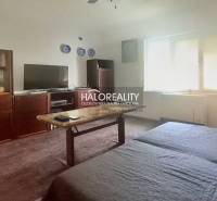 Wohnzimmer eines Einfamilienhauses mit älteren Möbeln, Fernseher und dekorativen Tellern an der Wand.