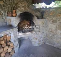 Ein steinerner Kamin im Inneren eines Einfamilienhauses, umgeben von Holz und Keramikdekorationen.