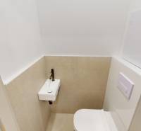 Kompakte Toilette mit Waschbecken in einer 2-Zimmer-Wohnung, beigefarbene Fliesen und weiße Wand.