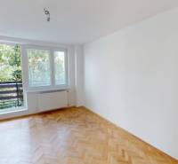 Ein geräumiges Zimmer in einer 2-Zimmer-Wohnung mit Holzboden und einem großen Fenster zum Balkon.
