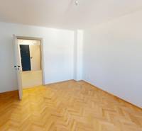 Ein Zimmer in einer 2-Zimmer-Wohnung mit Parkettboden und weißen Wänden.
