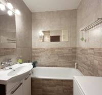 Badezimmer in einer 2-Zimmer-Wohnung mit Badewanne, Spiegel und Toilettenschrank.