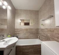 Badezimmer in einer 2-Zimmer-Wohnung mit Badewanne, Waschbecken und Fliesen in neutralen Tönen.