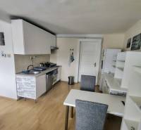 Küche in einer 2-Zimmer-Wohnung mit Esstisch, weißen Schränken und Holzboden.
