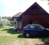 Ein Auto geparkt bei der Hütte in Klížska Nemá, umgeben von grünem Rasen und Bäumen.