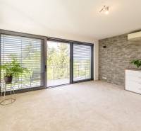 Ein Zimmer in einer 4-Zimmer-Wohnung mit großen Fenstern, Steinverkleidung und Pflanzen.