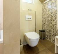 Badezimmer in einer 4-Zimmer-Wohnung mit Badewanne, Mosaikfliesen und Einbauschränken.