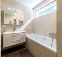 Badezimmer in einer 4-Zimmer-Wohnung mit Badewanne, Waschbecken, Spiegel und Fenster.