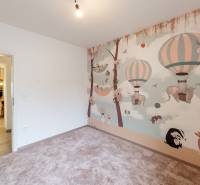 Kinderzimmer in einer 4-Zimmer-Wohnung mit farbiger Wand und Blick in die Küche.