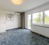 Ein Zimmer mit grauem Teppich und großem Fenster in einer 4-Zimmer-Wohnung.