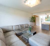 Wohnzimmer mit Sofa, Glastisch und offener Küche in einer Vierzimmerwohnung.