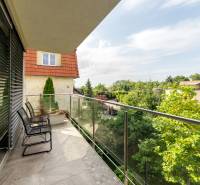 Ein Balkon mit Sitzgelegenheit in einer 4-Zimmer-Wohnung, umgeben von Grün und mit Blick auf die Cesta na Klanec, Bratislava - Lamač.