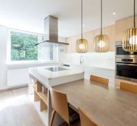 Küche in einer 4-Zimmer-Wohnung mit Insel, Holzelementen und großem Fenster.