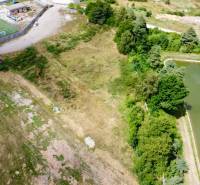 Luftaufnahme von Entwicklungsgrundstücken in Záhradné mit einem nahegelegenen Fußballplatz und einem Teich.