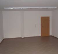 Leerer Büroraum mit braunen Fliesen und Holztüren.
