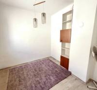 Ein Zimmer in einem Einfamilienhaus mit einem lila Teppich, einer Holzleuchte und einem eingebauten Regal.