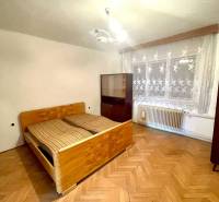 Das Innere eines Einfamilienhauses mit Holzboden, Bett und Vorhängen am Fenster.