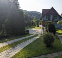 Ein Einfamilienhaus in Nová Baňa mit Zufahrtsstraße, umgeben von Grün und Hügeln.