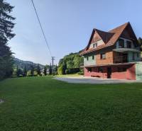 Ein Einfamilienhaus in Nová Baňa mit Rasen und einer Umgebung voller Bäume und Hügel.