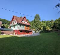 Ein Einfamilienhaus in Nová Baňa, umgeben von Grünflächen, mit einem Hof und Bäumen in der Umgebung.