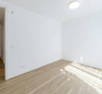Ein leeres Zimmer in einer 3-Zimmer-Wohnung mit Holzboden und weißen Wänden.