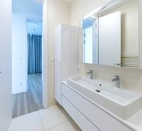 Badezimmer mit Waschbecken und Spiegel in einer 3-Zimmer-Wohnung, Blick in den Raum mit Holzboden.