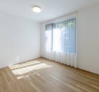 Ein leerer Raum mit einem Fenster und einem Boden in Holzoptik in einer 3-Zimmer-Wohnung.