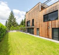 Eine Holzfassade des Hauses, umgeben von einem gepflegten Rasen und einer Hecke an der Devínska cesta.