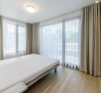 Helles Schlafzimmer mit großen Fenstern und Holzboden in einer 3-Zimmer-Wohnung.