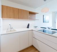 Küche in einer 2-Zimmer-Wohnung mit weißen Schränken, Holzelementen und großem Fenster.