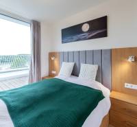Schlafzimmer in einer 2-Zimmer-Wohnung mit Balkon, Holzmöbeln und einem Bild mit Mond.