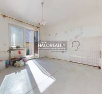 Ein leerer Raum in einem Einfamilienhaus mit Terrassentüren und Vorbereitung für eine Küche.