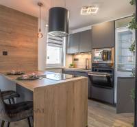 Küche in einer 3-Zimmer-Wohnung mit Holztheke, Geräten und moderner Beleuchtung.