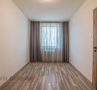 Ein leerer Raum mit Holzboden und einem Fenster mit dunklen Vorhängen in einer 3-Zimmer-Wohnung.