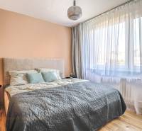 Schlafzimmer mit Bett, Vorhängen und Hängelampe in einer 3-Zimmer-Wohnung.