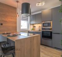 Küche in einer 3-Zimmer-Wohnung mit Holzelementen, modernen Geräten und einer Essbar.