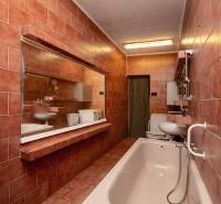 Ein Badezimmer mit rosa Fliesen, einer Badewanne, einem Waschbecken und einem Spiegel in einem Einfamilienhaus.