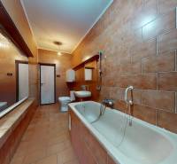 Ein Badezimmer in einem Einfamilienhaus mit beigen Fliesen und einer Badewanne.