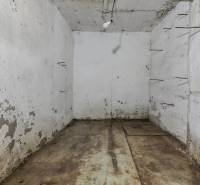 Ein abgenutzter Keller in einem Einfamilienhaus mit Beleuchtung und Metallvorsprüngen an der Wand.
