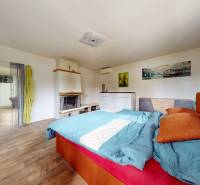 Schlafzimmer im Einfamilienhaus mit Kamin, Bett und Holzboden.
