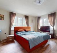 Schlafzimmer in einem Einfamilienhaus mit einem orangefarbenen Bett, einem Sessel und einem Fernseher.